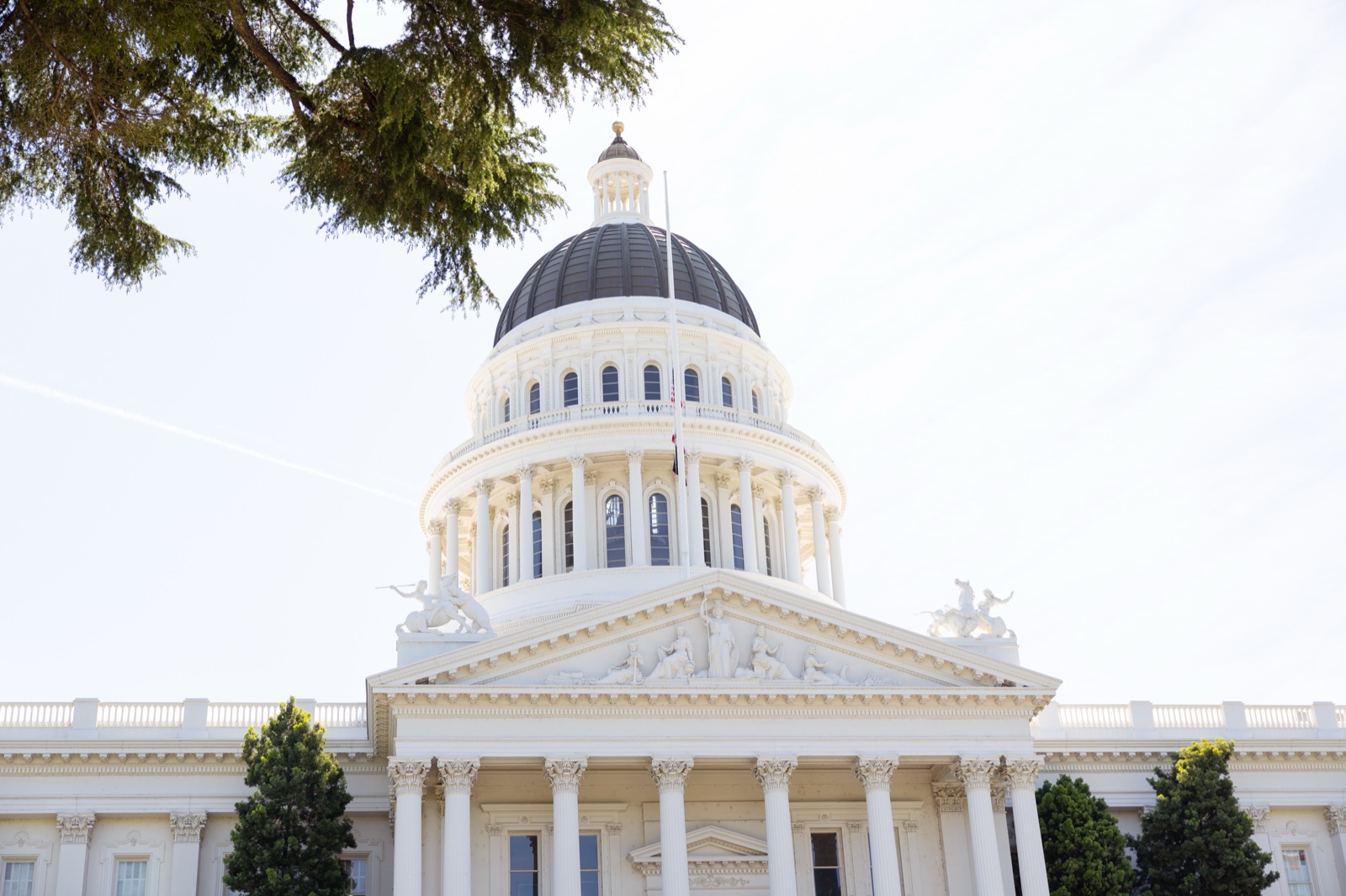 California State Capitol building with its white dome and columns under a bright sky.